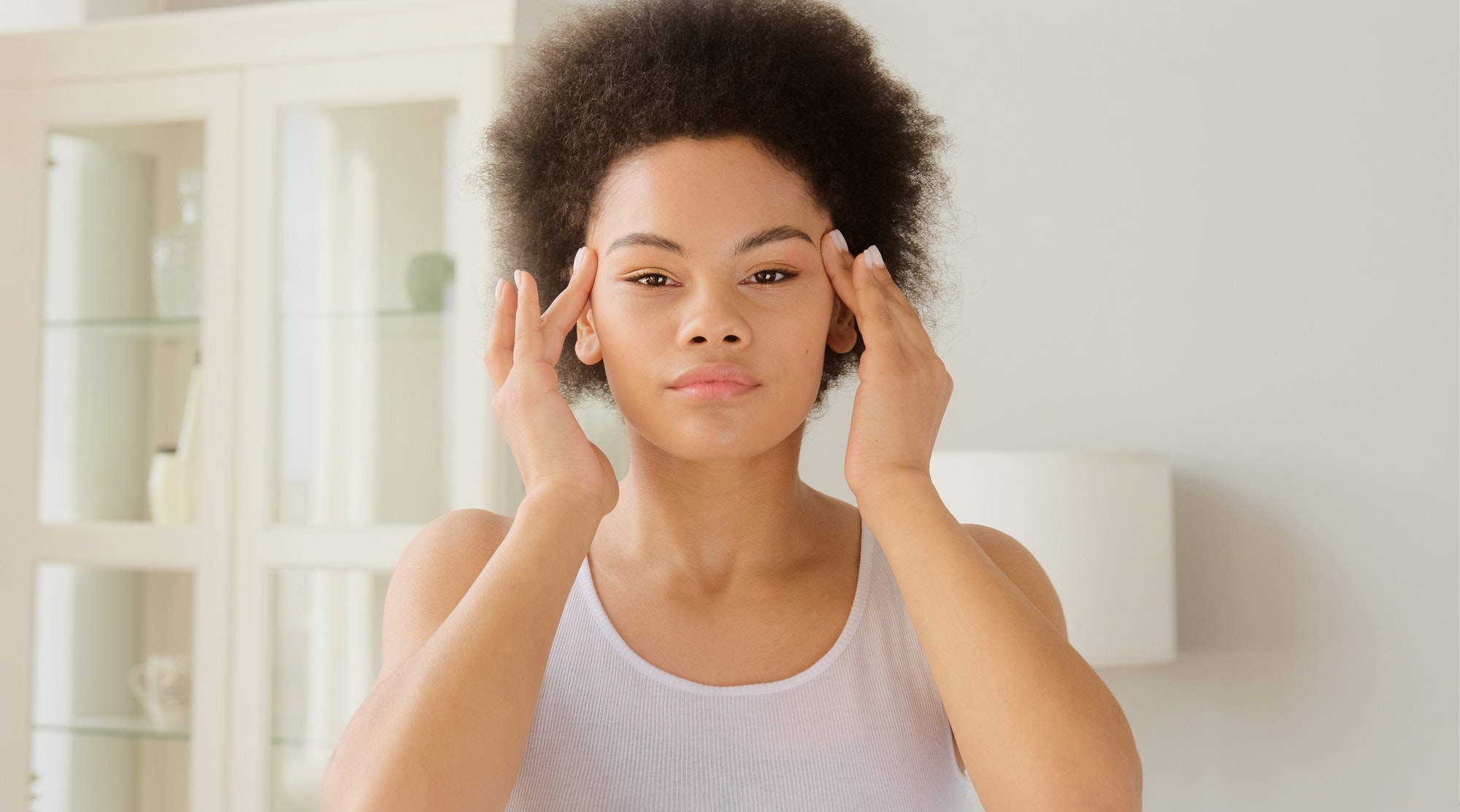 African american woman makes herself a face lifting massage